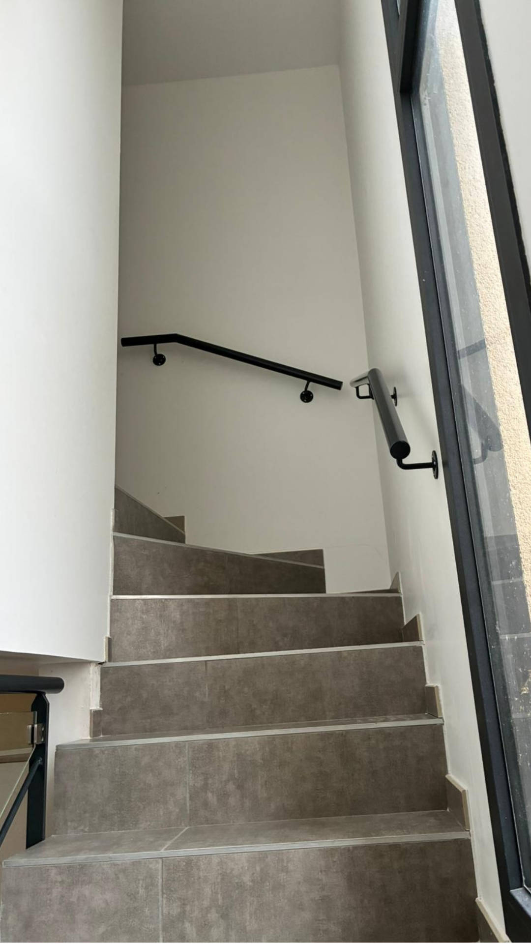 Main courante et garde-corps en acier avec verre sur mesure install&eacute;s le long d&rsquo;un escalier int&eacute;rieur