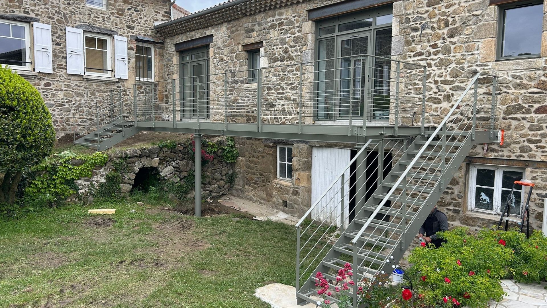 Terrasse m&eacute;tallique sur&eacute;lev&eacute;e avec deux escaliers et garde-corps en acier gris &agrave; Peaugres